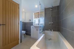 a bathroom with a tub and a sink and a toilet at Yew Tree Cottage in Westleton +20 photos