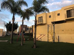 a playground in a yard with two palm trees at Tijuana descanso in Harry Manzo