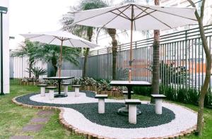 two picnic tables and an umbrella in a garden at SanLoft Expo Inn Tietê 02 Top 1 in Sao Paulo