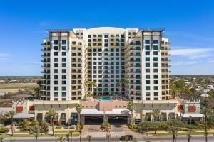 twee hoge witte gebouwen met palmbomen en een parkeerplaats bij “Lotusland” Origin at Seahaven! in Panama City Beach