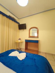 a bedroom with a blue bed and a tv at Studios Dafni in Paralia Katerinis