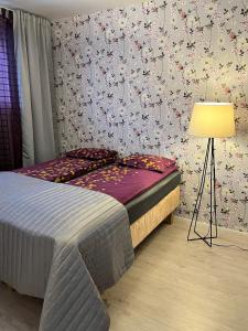 ein Schlafzimmer mit einem Bett mit einer Lampe und Blumen an der Wand in der Unterkunft 4 km to the Jyväskylä city center afoot, cute apartment with free parking in Jyväskylä