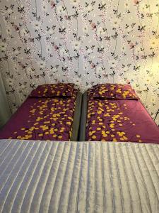 2 Betten in einem Schlafzimmer mit einer Wand mit Blumen in der Unterkunft 4 km to the Jyväskylä city center afoot, cute apartment with free parking in Jyväskylä