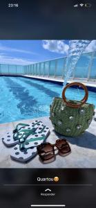 a television screen with a purse and sunglasses next to a swimming pool at FHF Blue Suites in João Pessoa