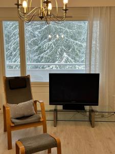 uma sala de estar com uma televisão, uma cadeira e uma janela em 4 km to the Jyväskylä city center afoot, cute apartment with free parking em Jyväskylä