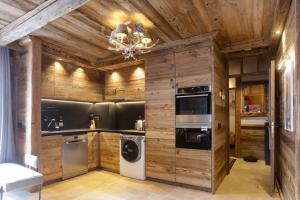 cocina con paredes de madera, lavadora y secadora en Résidence Deu Sol appartement Chalet Vall d Incles en Canillo