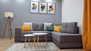 ein Wohnzimmer mit einem grauen Sofa und 2 Tischen in der Unterkunft Vila Harmony in Pirot