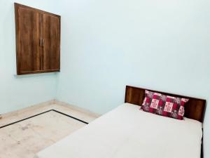 1 dormitorio con 1 cama blanca y armario en Nisha Homestay, en Aligarh