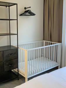 - un lit bébé dans une chambre à côté d'une commode dans l'établissement Olive Beach, luxury beachhouse 150 m from the beach, à Noordwijk aan Zee