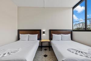 two beds in a room with two windows at Suites Reforma by HomiRent in Mérida