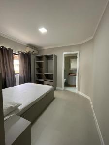 a white bedroom with a bed and a room with at APARTAMENTO BEIRA MAR EM BALNEÁRIO PEREQUÊ in Porto Belo
