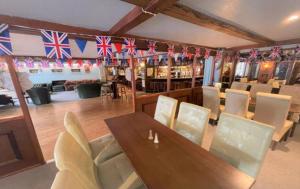 uma sala de jantar com mesa, cadeiras e bandeiras em The Sportsmans Inn Limited em Ivybridge