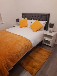 uma cama com almofadas cor-de-laranja e brancas em Modern flat near city centre. em Edimburgo