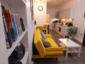 uma sala de estar com uma cadeira amarela e uma cozinha em Modern flat near city centre. em Edimburgo
