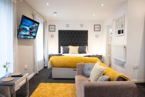 a bedroom with a bed and a couch and a tv at Dealhouse Apartments 11 in Huddersfield