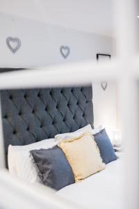 1 cama con cabecero gris y almohadas en Dealhouse Apartments 11, en Huddersfield