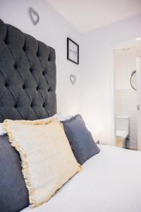 1 cama con cabecero acolchado negro y almohada en Dealhouse Apartments 11 en Huddersfield