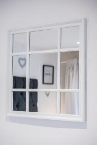espejo en una habitación blanca con ventana en Dealhouse Apartments 11, en Huddersfield