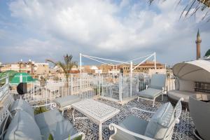 un patio con sillas blancas y mesas en el techo en Villa Sera, en Acre