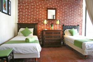 een slaapkamer met 2 bedden en een bakstenen muur bij Villa Esperanza in Ticumán