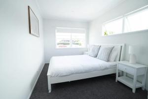 a white bedroom with a white bed and a window at Bright & Central Home in Auckland