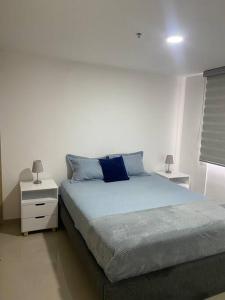 a bedroom with a bed with blue pillows on it at Hermoso, moderno y confortable apartamento. in Bello