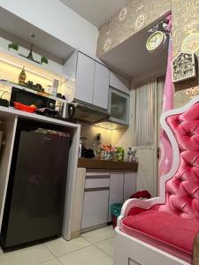uma pequena cozinha com uma cadeira rosa num quarto em Homestay Jakarta em Pondokcabe Hilir