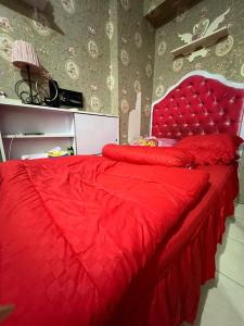 a red bed with a red comforter in a bedroom at Homestay Jakarta in Pondokcabe Hilir
