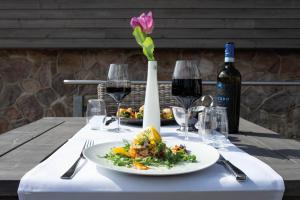 una mesa con un plato de comida y copas de vino en StrandBerg's Designhotel Viktoria en Braunlage