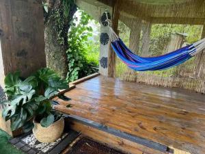 a hammock on a wooden deck with a tree at Casa Bali PR in Guayama