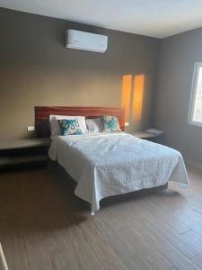 een slaapkamer met een bed met een wit dekbed bij Casa Maravatío M R in Playa Azul