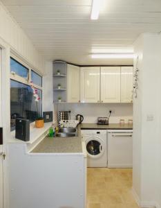 cocina blanca con fregadero y lavavajillas en SPACIOUS 3 BED HOUSE WITH PARKING & GOOD TRANSPORT en South Norwood