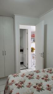 a white bedroom with a bed and a kitchen at Ótimo Ap na Pajuçara - Maceió in Maceió