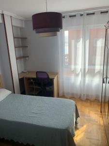 a bedroom with a bed and a desk and a window at Apartamento Santander in Santander