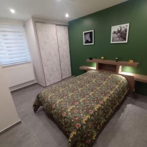 een slaapkamer met een bed en een groene muur bij Au cœur de Barr - Le p'tit Ritz in Barr