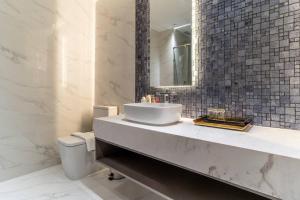 uma casa de banho com um lavatório, um espelho e um WC. em The Rixx Central @ Park Hyatt/SmartTV65in/Netflix em Ho Chi Minh