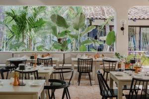 un restaurante con mesas, sillas y plantas en Sendero Hotel, en Nosara