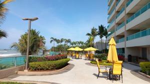 a hotel patio with chairs and umbrellas and the beach at Acogedor departamento con playa privada in Salinas