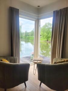a living room with a large window with a view of a lake at Slapenopdewaal in Beneden-Leeuwen