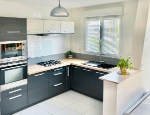 a kitchen with black and white cabinets and a stove at Location maison Jardin Gîte Angers Les Ponts de Cé in Les Ponts-de-Cé