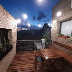 una terraza de madera con una mesa de madera y un banco en Hermoso departamento entero 2 Dormitorios con cochera B Urca en Córdoba