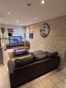 uma sala de estar com um sofá e um relógio na parede em Les 4 chênes - T2 refait à neuf em Le Pont-de-Beauvoisin