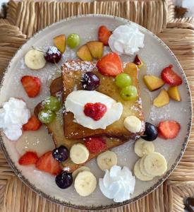 a plate of waffles with fruit and whipped cream at 4 Ambelia paradise in Megalochori
