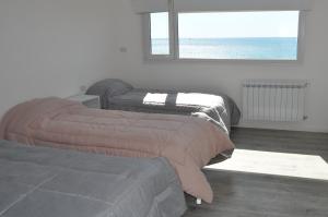 two beds in a room with a window at Edificio Frente al Mar - Amplios departamentos in Caleta Olivia