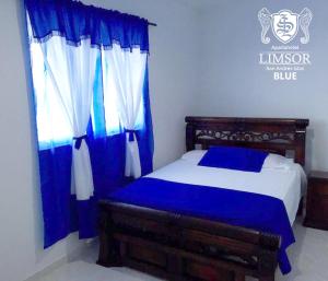 a bedroom with a blue and white bed and a window at Apartahotel Limsor Blue in San Andrés