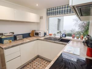 a kitchen with white cabinets and a sink and a window at Helm Crag in Grasmere