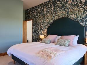 a bedroom with a large bed with a floral wallpaper at The Cart House in Duns