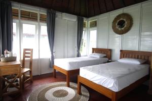 a bedroom with two beds and a desk and windows at PASERANG PARIRI PARADISE in Labuberu