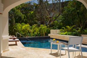 a swimming pool in a garden with a table and chairs at Secrets Royal Beach Punta Cana - Adults Only in Punta Cana