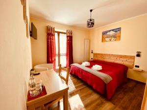 a bedroom with a red bed and a desk and window at Hotel Piccolo Chalet in Claviere